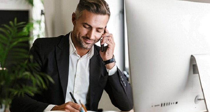 un homme est au téléphone et prend des notes au même moment